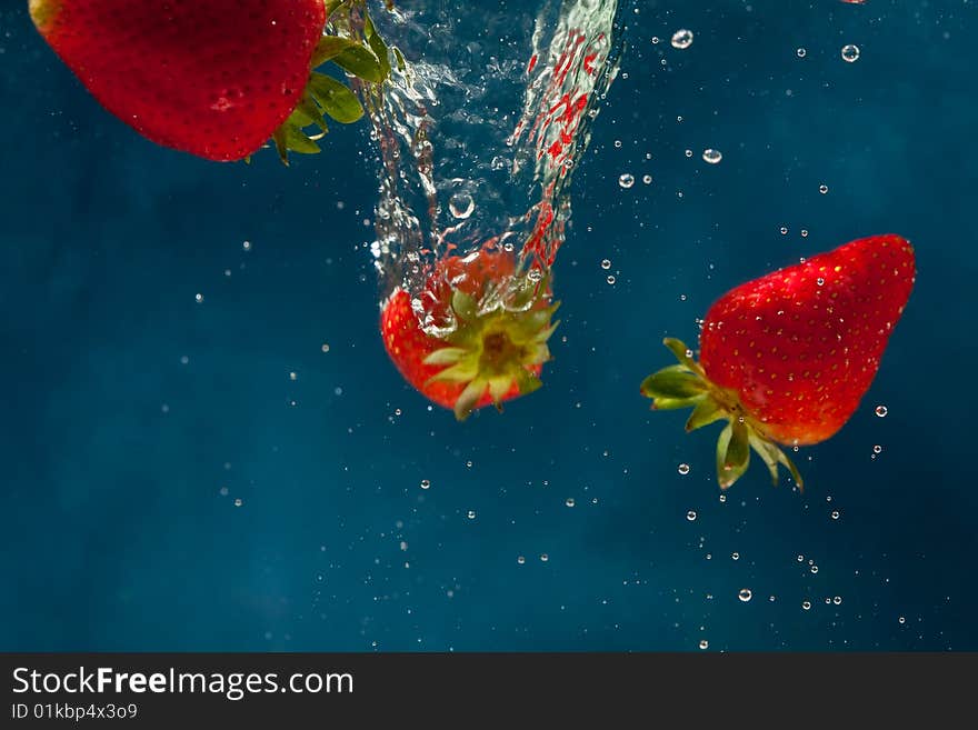 Fresh strawberries dropped into water