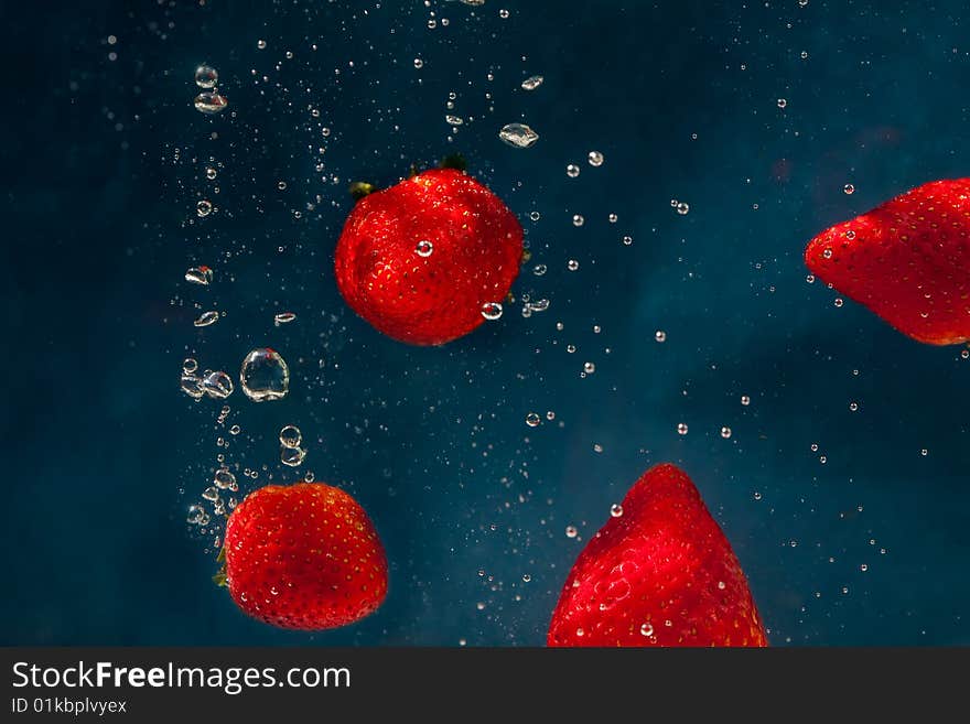 Fresh strawberries dropped into water