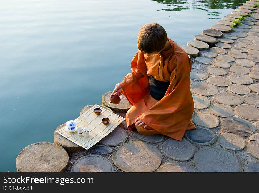 Master of tea ceremony pouring tea near a lake. Master of tea ceremony pouring tea near a lake