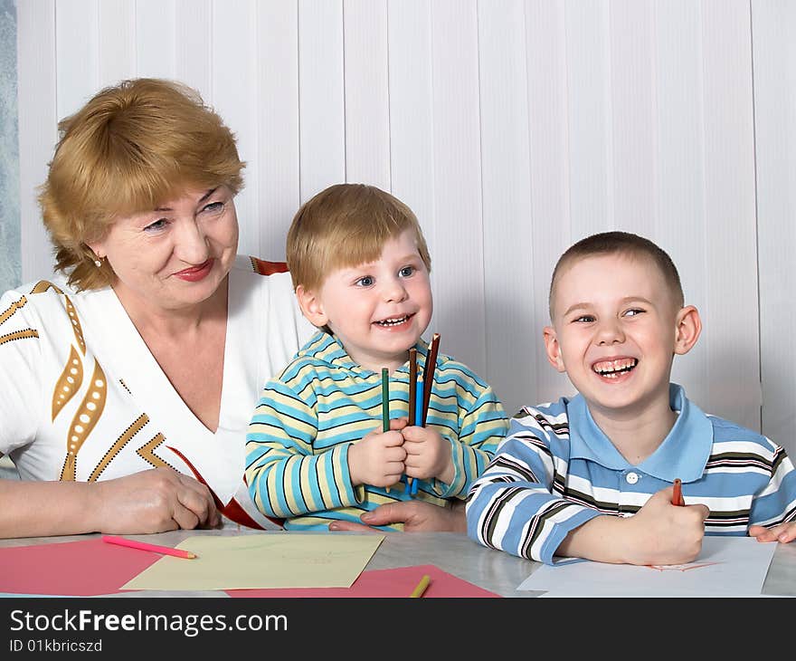 The grandmother is engaged in drawing with two grandsons. The grandmother is engaged in drawing with two grandsons