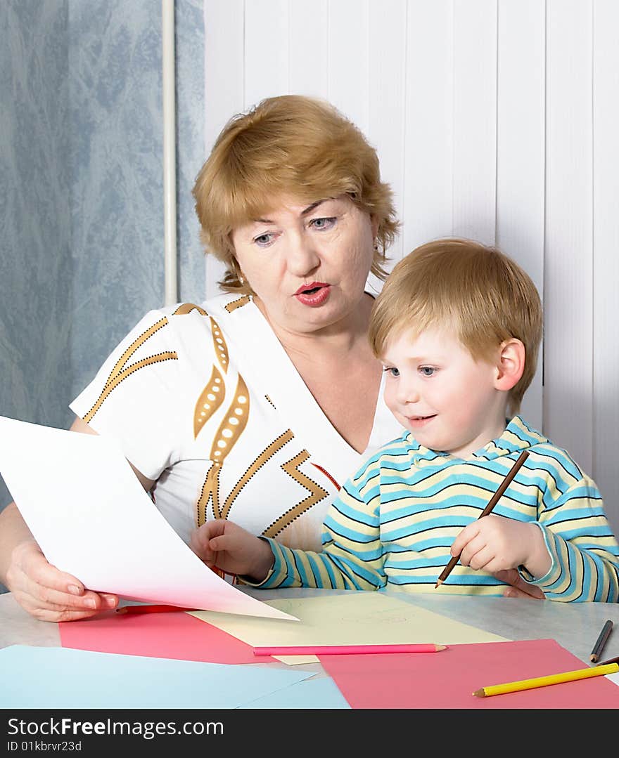 The grandmother with grandson is engaged behind a table. The grandmother with grandson is engaged behind a table