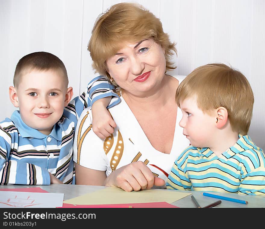 The grandmother is engaged in drawing with two grandsons. The grandmother is engaged in drawing with two grandsons