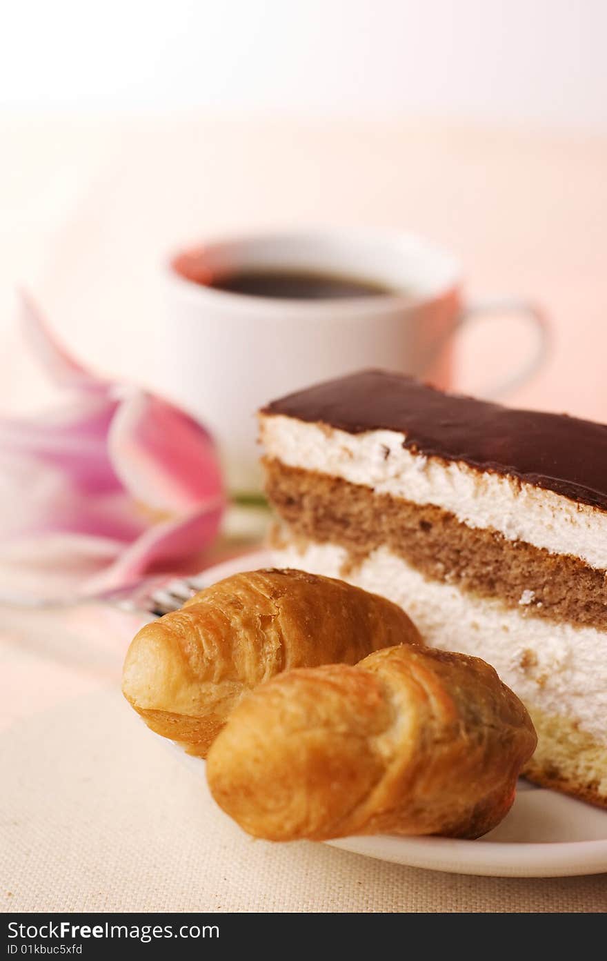 Pastry in the saucer and coffee on the tablecloth. Pastry in the saucer and coffee on the tablecloth