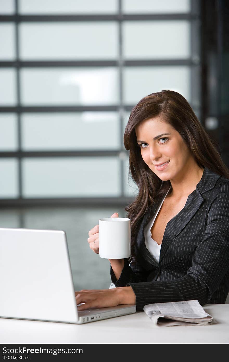 Business woman in modern office with laptop and coffee. Business woman in modern office with laptop and coffee