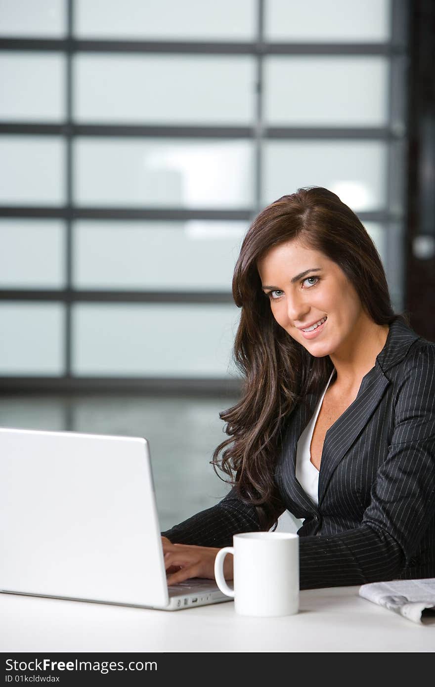 Business woman in modern office with laptop and coffee. Business woman in modern office with laptop and coffee