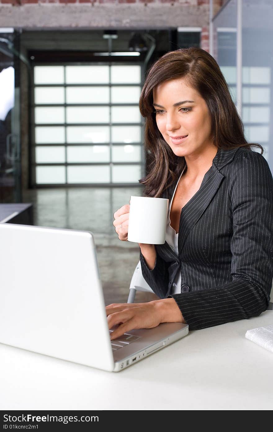 Business woman in modern office with laptop and coffee. Business woman in modern office with laptop and coffee