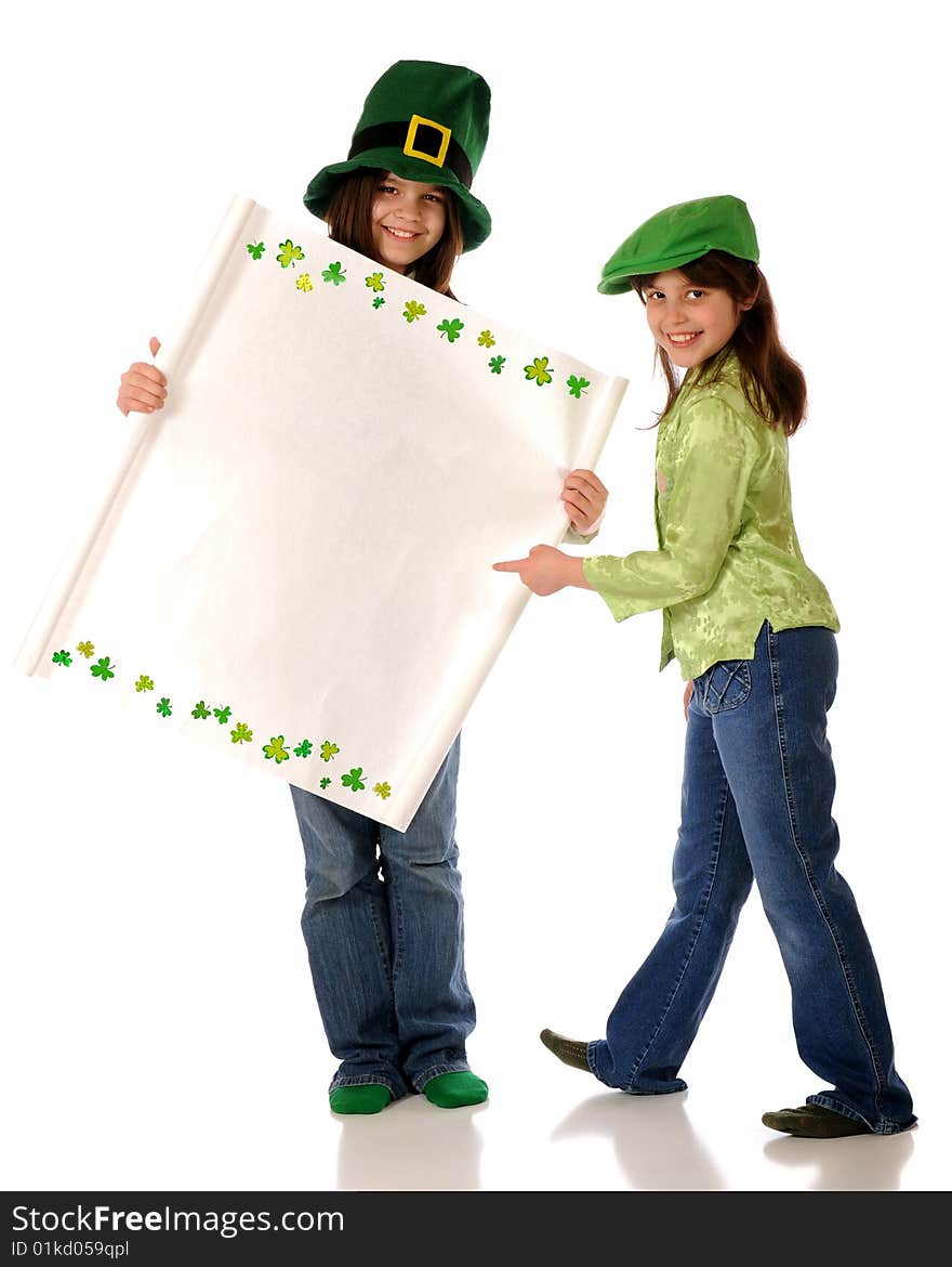 Two girls dressed for St. Patrick's Day. One holds a blank sign (for your message) with a shamrock border. The other points happily to it. Two girls dressed for St. Patrick's Day. One holds a blank sign (for your message) with a shamrock border. The other points happily to it.