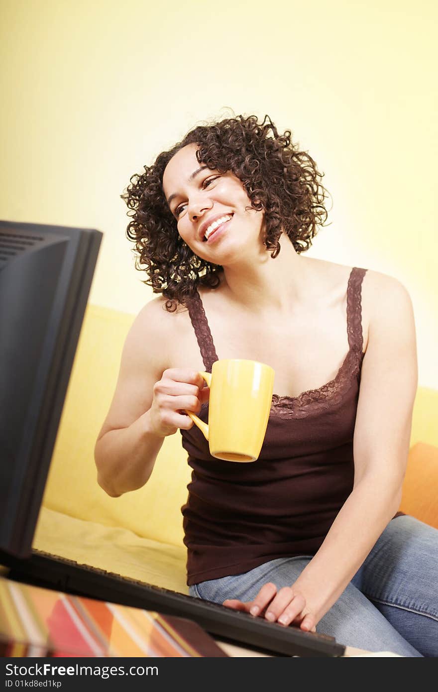 Cheerful young woman working at home with a cup of coffee. Cheerful young woman working at home with a cup of coffee