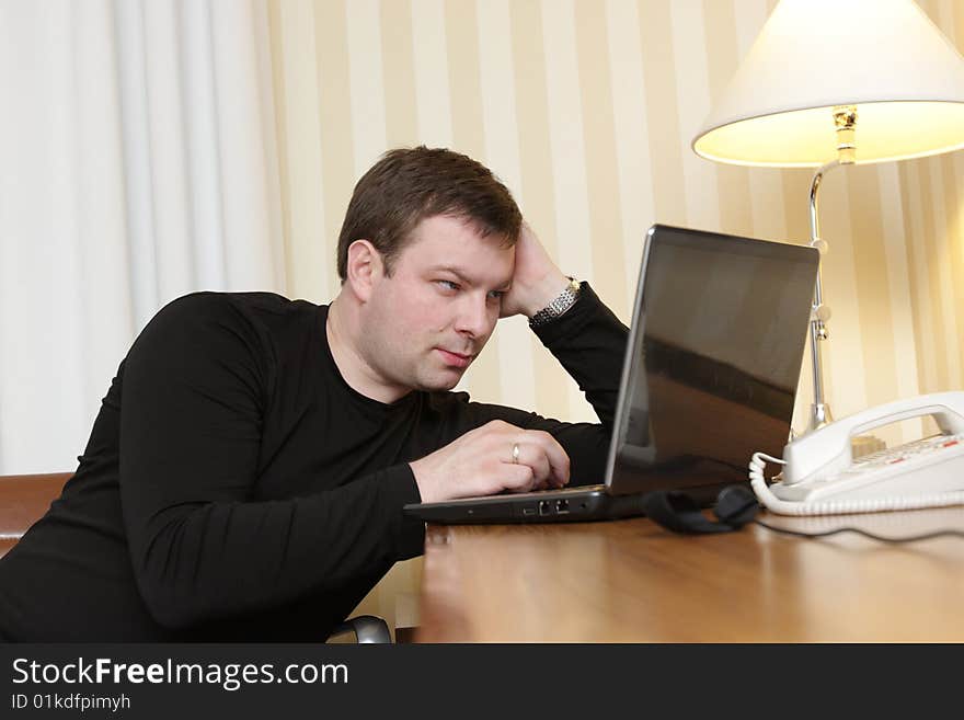 The man watches a film on laptop in a hotel. The man watches a film on laptop in a hotel