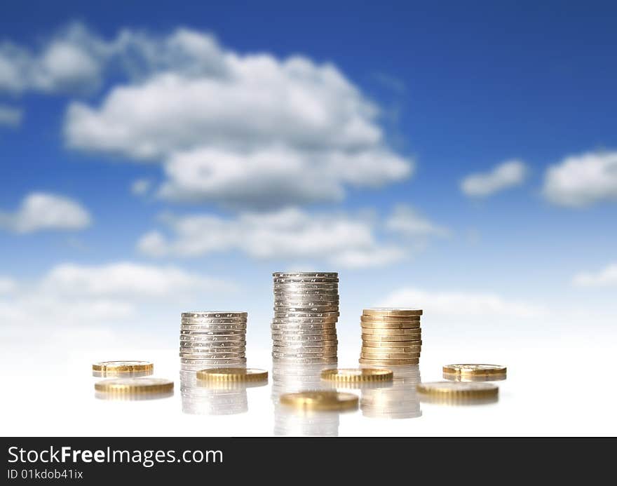 Coins on a glass table. Financial concept. Over blue sky background.