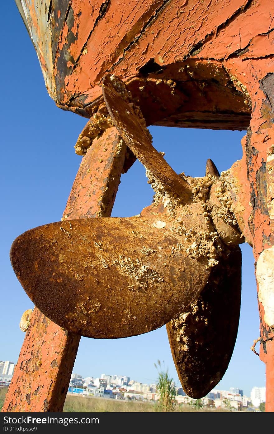 Ship propeller in a dock and a town on a background. Ship propeller in a dock and a town on a background