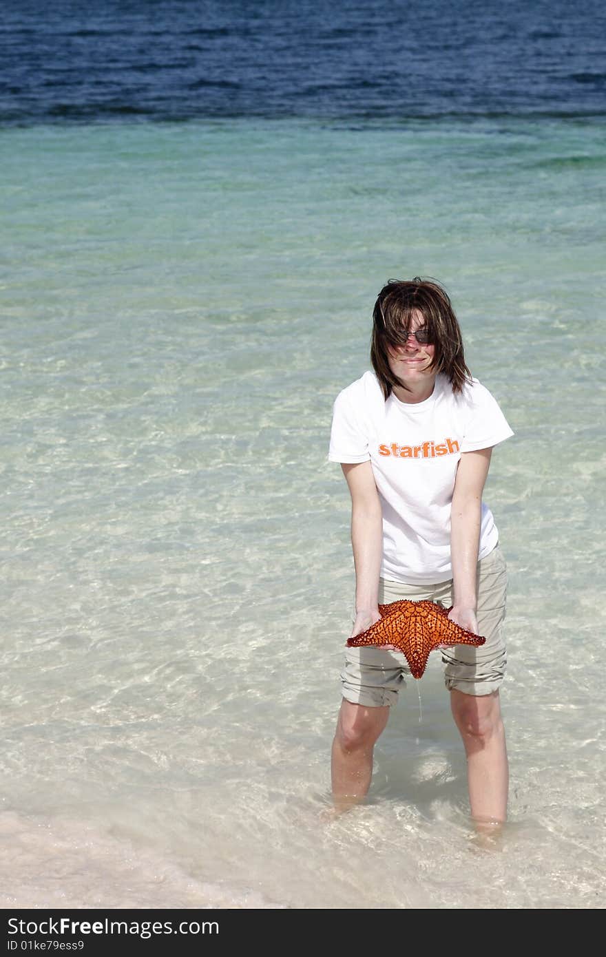 Woman with starfish shirt holding a red custion seastar starfish. Woman with starfish shirt holding a red custion seastar starfish