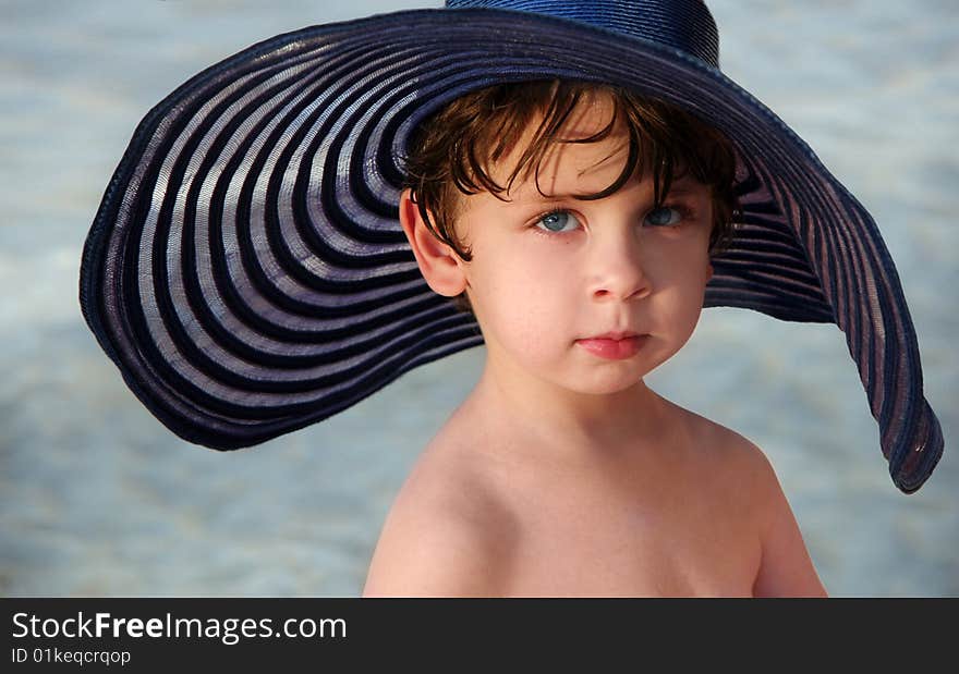 A little boy in a big blue hat. A little boy in a big blue hat