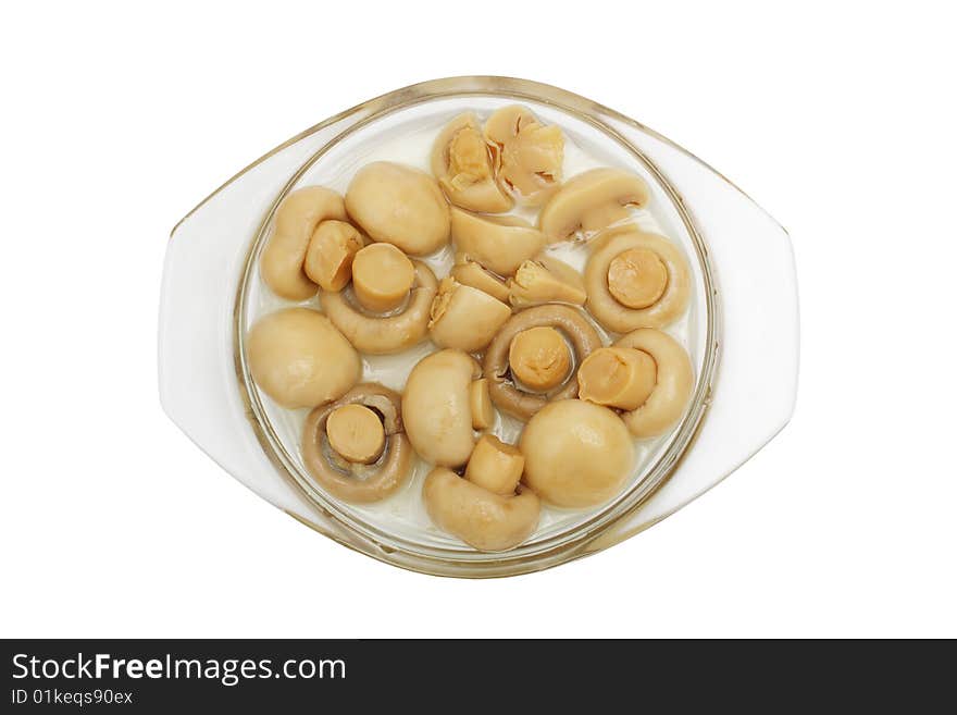 The tinned champignons in a plate are isolated on a white background