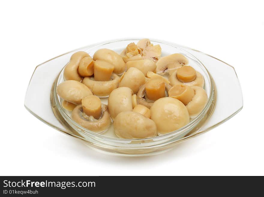 The tinned champignons in a plate are isolated on a white background