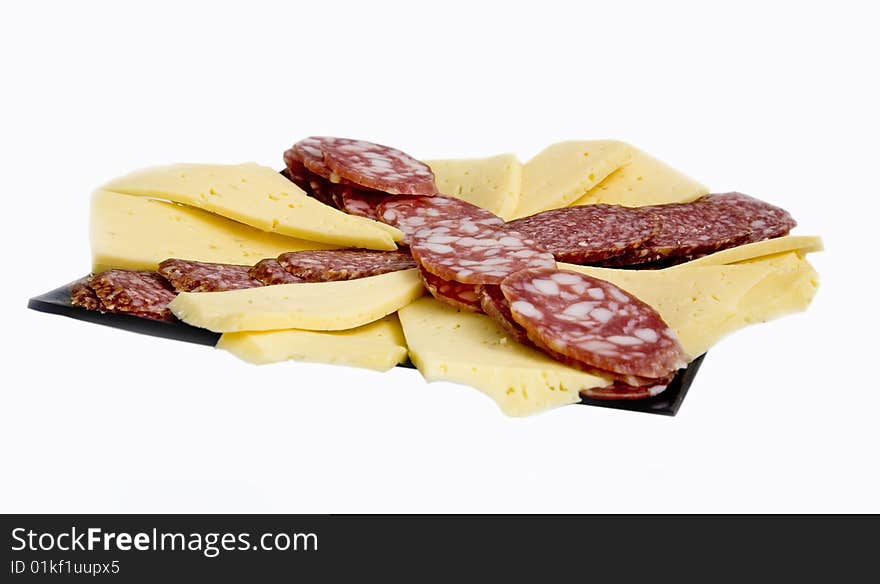 The cut cheese and sausage on a glass black plate