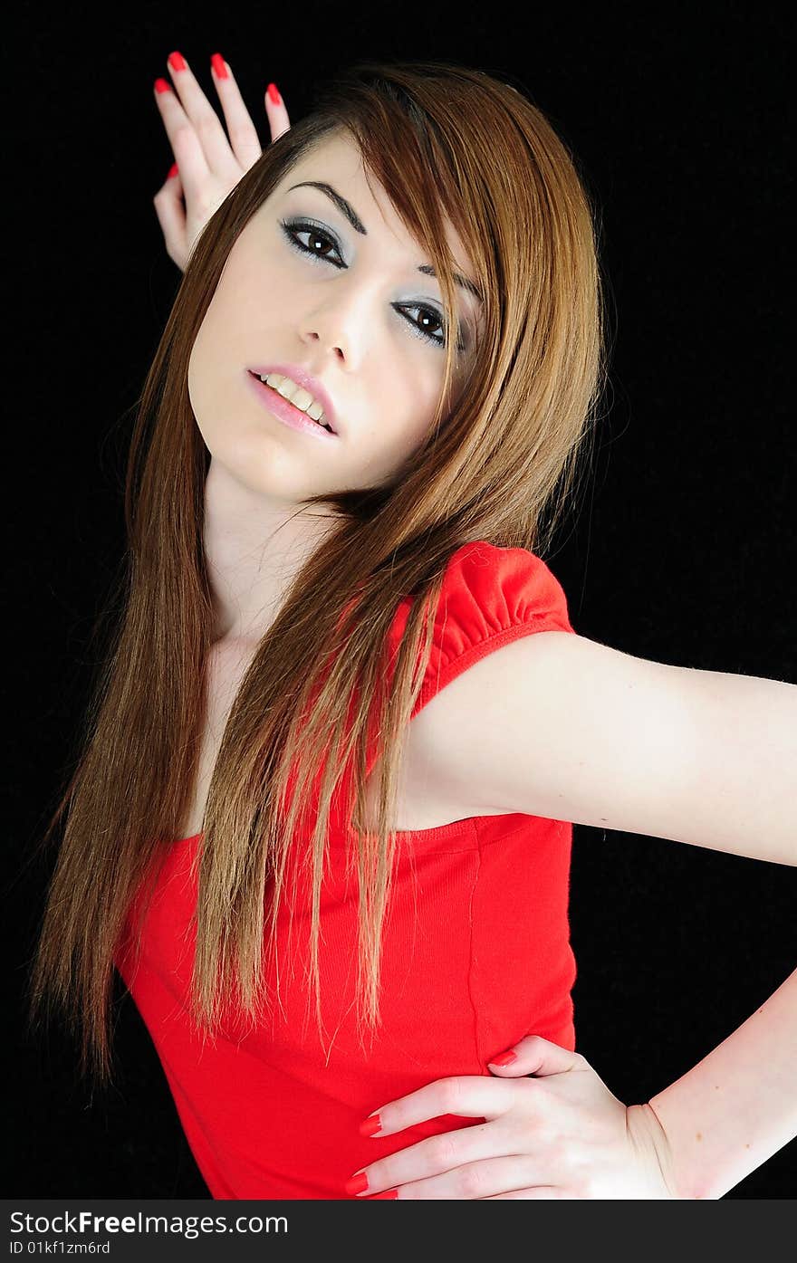 Female fashion model with strong facial make up and a bright red top. Shes standing against a black backdrop with long straight brunette hair. Female fashion model with strong facial make up and a bright red top. Shes standing against a black backdrop with long straight brunette hair