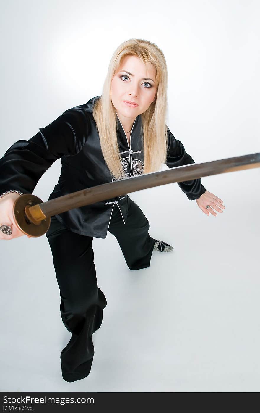 Woman in Japanese shirt with sword, studio shot