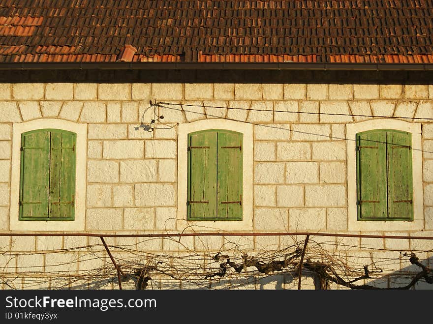 Old stone house with green wooden windows.