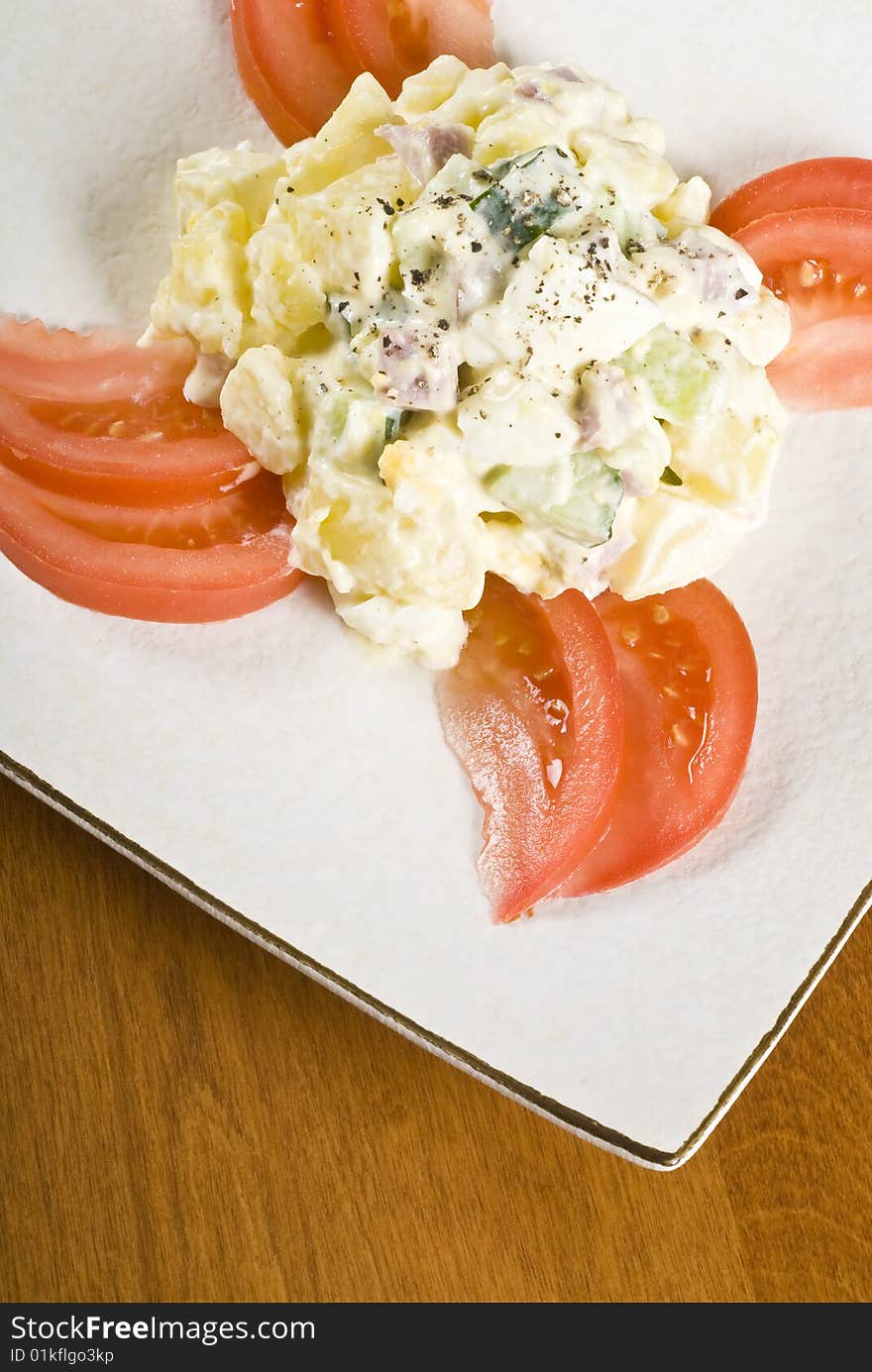 A plate of potato salad decorated with tomato slices.