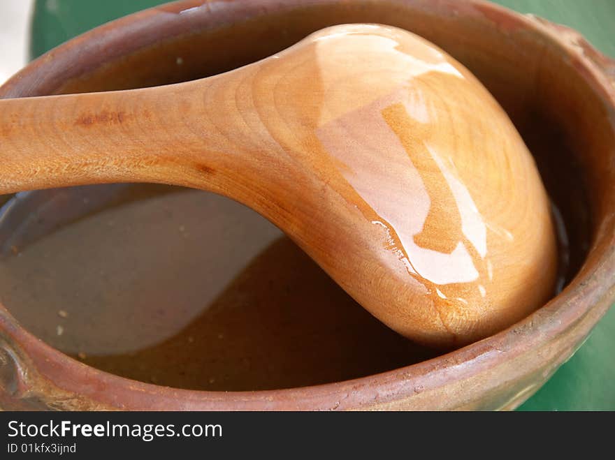 Yellow wooden spoon in brown earthenware closeup. Yellow wooden spoon in brown earthenware closeup