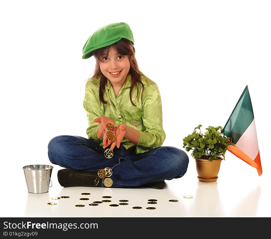 An older elementary girl dressed for St. Patrick's Day while displaying a handful of gold coins.  A golden pot of shamrocks and an Irish flag are nearby. An older elementary girl dressed for St. Patrick's Day while displaying a handful of gold coins.  A golden pot of shamrocks and an Irish flag are nearby.