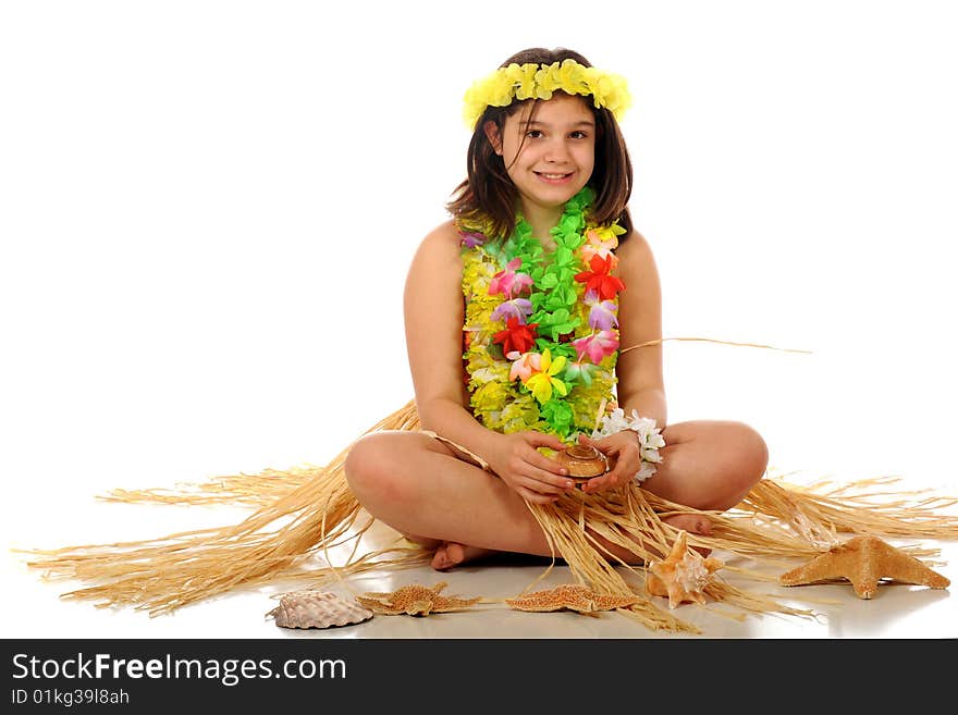 A preteen girl dressed in Hawaiian leis and a grass skirt sitting among star fish and shells. Isolated on white. A preteen girl dressed in Hawaiian leis and a grass skirt sitting among star fish and shells. Isolated on white.