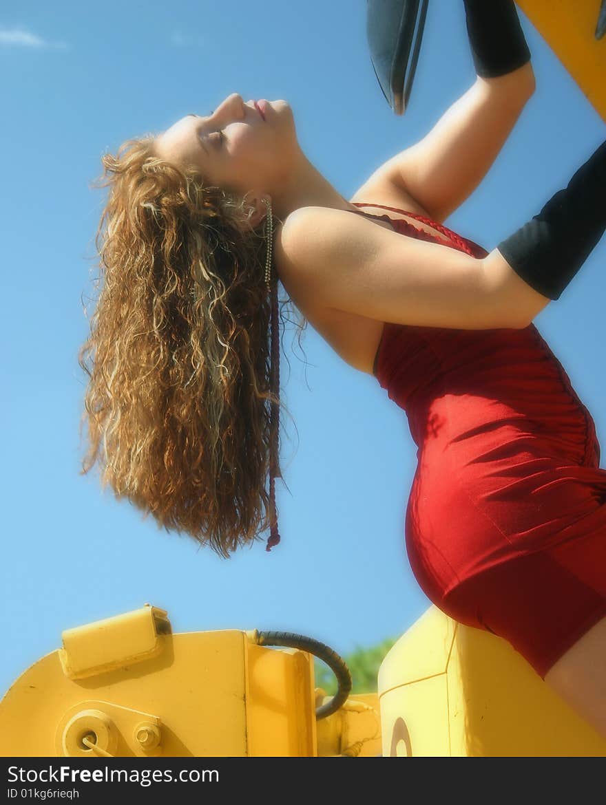 Woman In Red Dress Hangs From Bulldozer