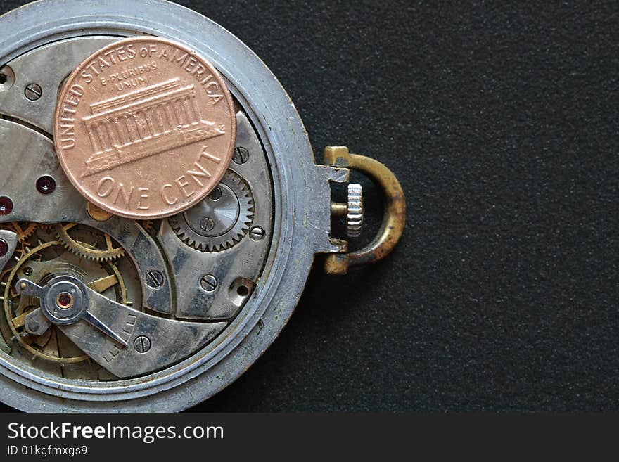 USA one cent coin lying on watch mechanism. Isolated on black. USA one cent coin lying on watch mechanism. Isolated on black