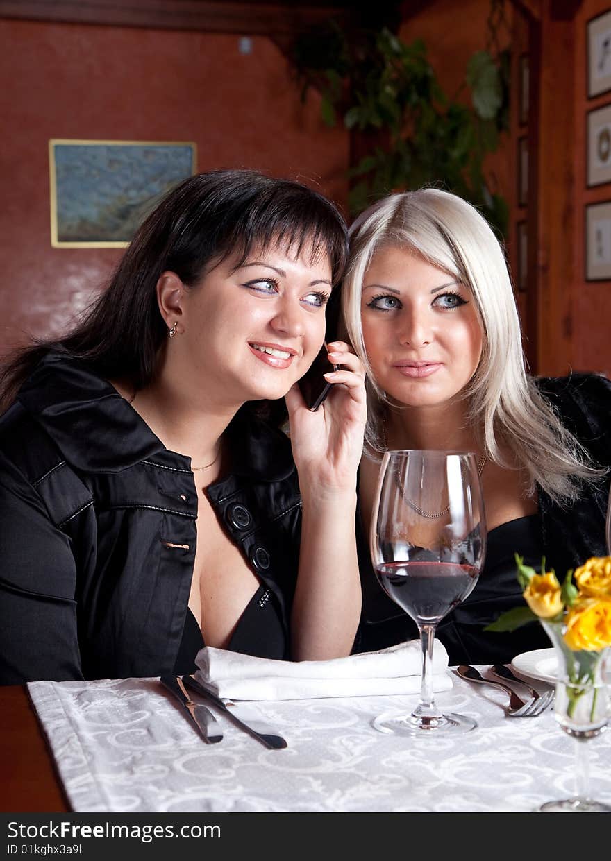 Two young women listen to a conversation on the phone