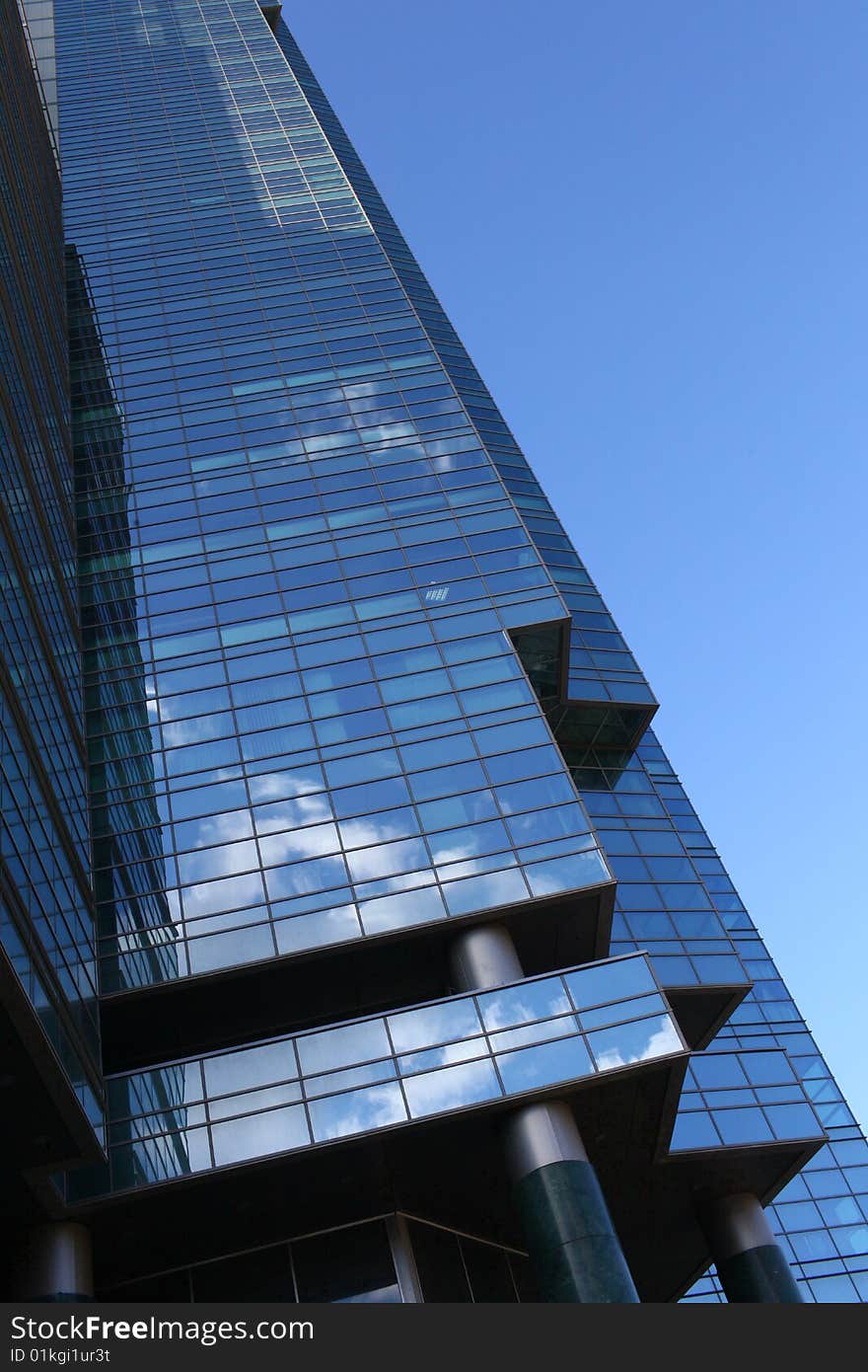 The sky and clouds are reflected in windows of a modern building. The sky and clouds are reflected in windows of a modern building