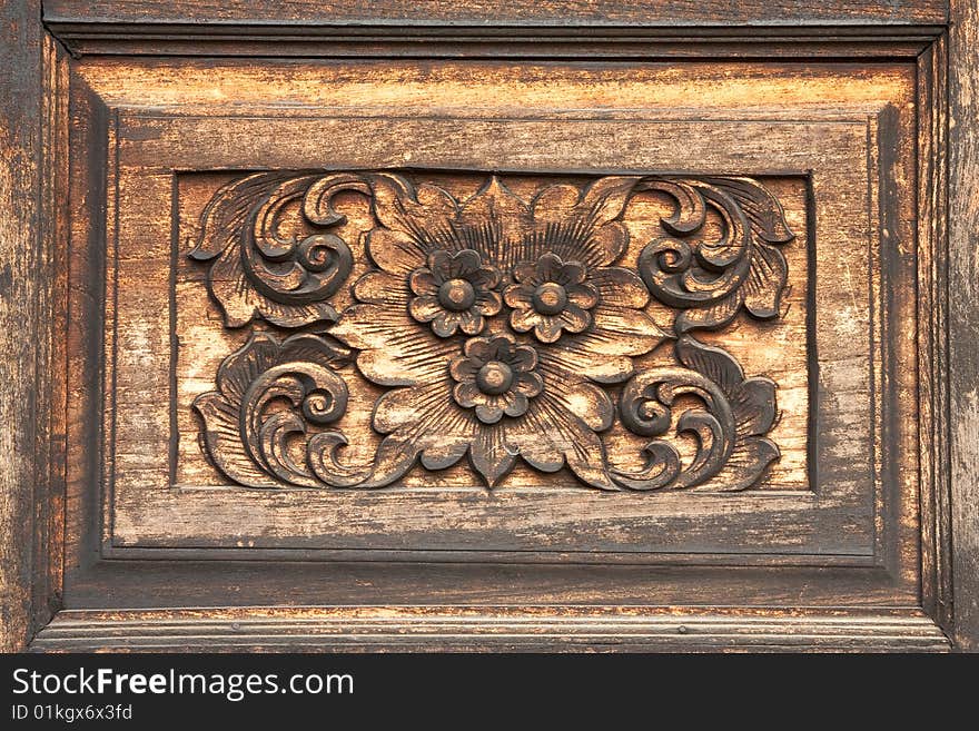 Flower in traditional Thai style wood carving on wall of Buddhist church