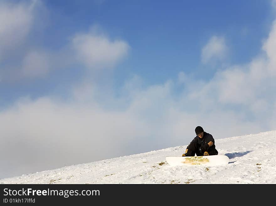 Man with snowboard sitting on slope