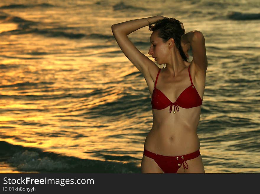 Woman in red bikinis on the beach by sunset. Woman in red bikinis on the beach by sunset