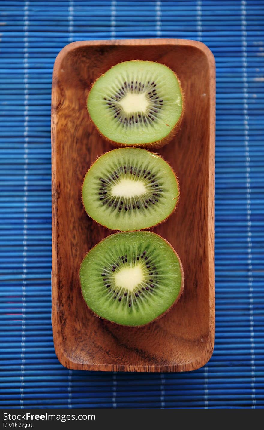 Three half of kiwi in a wooden plate
