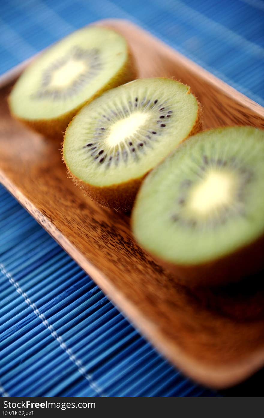 Three half of kiwi in a wooden plate