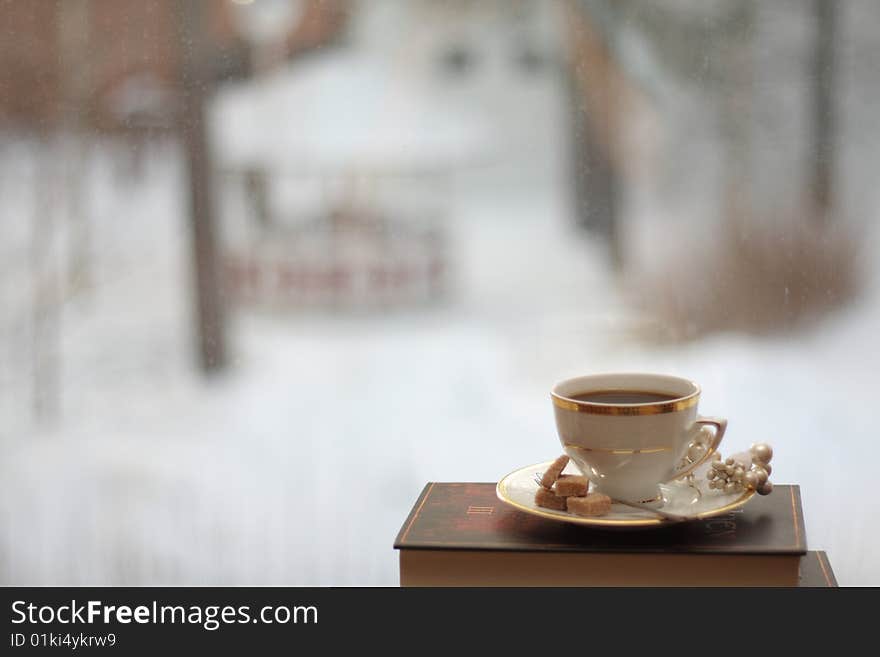 Porcelain cup with coffee on a stack of books by the window. Porcelain cup with coffee on a stack of books by the window