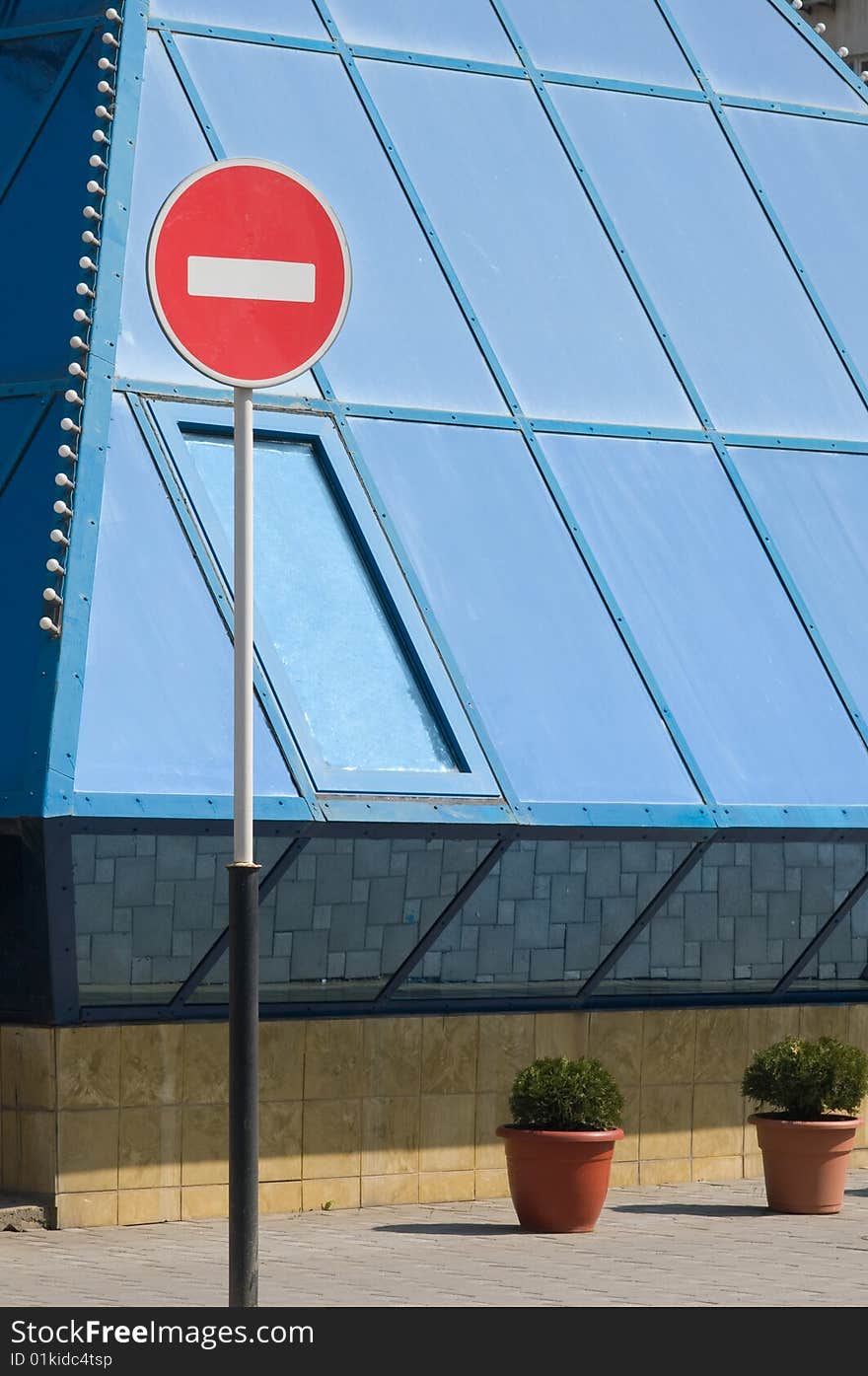 Red forbidding traffic sign against blue windows of a building. Red forbidding traffic sign against blue windows of a building.