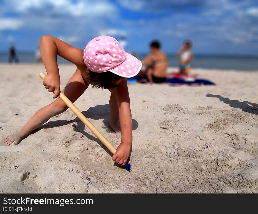 Hardworking girl shoveling sand at the beach