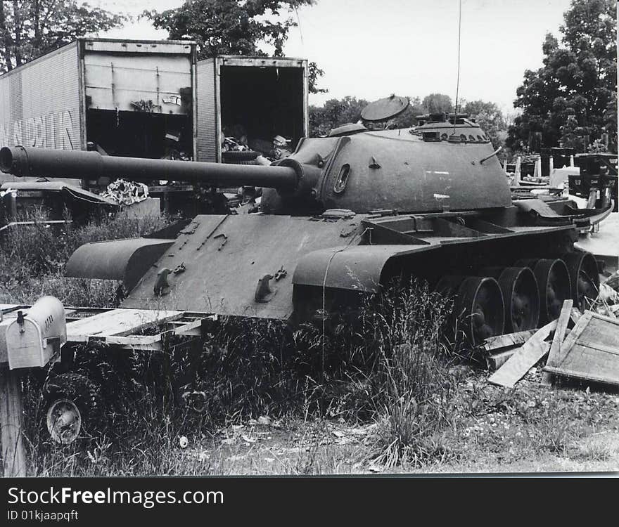 Black and white photo of an old, retired tank in a junkyard.