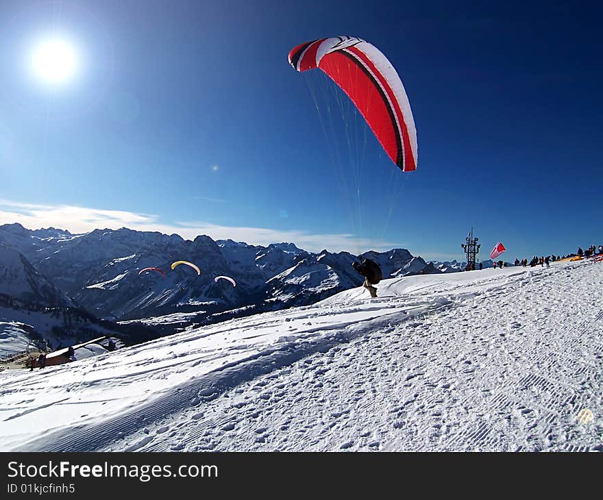 Paraglider taking off from a snowy hill. Paraglider taking off from a snowy hill