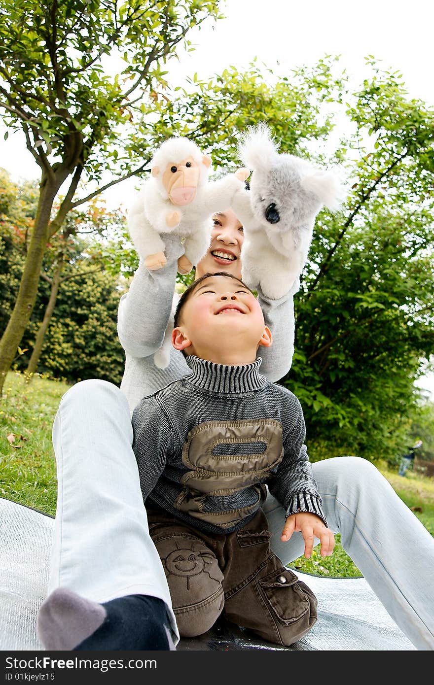 A picture of a little chinese boy and his mother playing plush toys together and having great fun. A picture of a little chinese boy and his mother playing plush toys together and having great fun