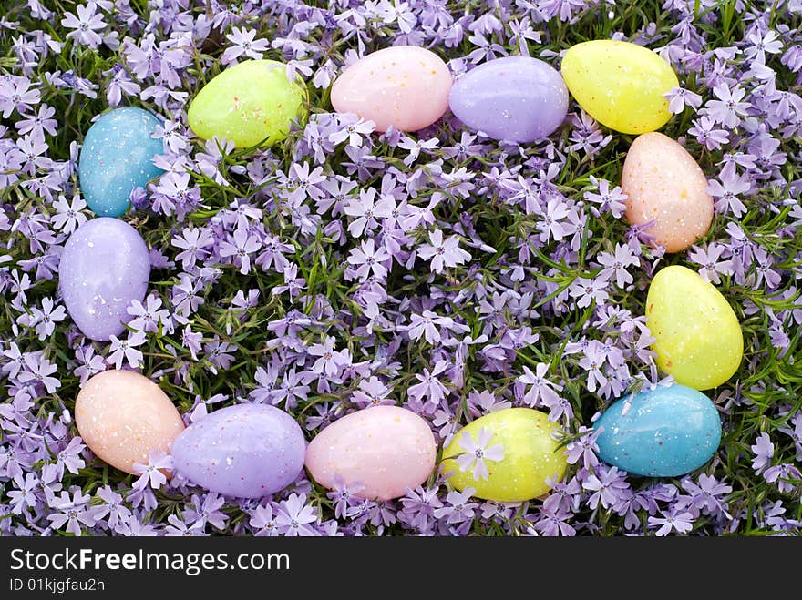 A rectangle border of colored Easter Eggs on a background of fresh purple Phlox blooms. A rectangle border of colored Easter Eggs on a background of fresh purple Phlox blooms