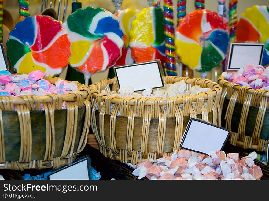 Baskets filled with taffy with blank signs, with colorful lollipops in the background. Baskets filled with taffy with blank signs, with colorful lollipops in the background.