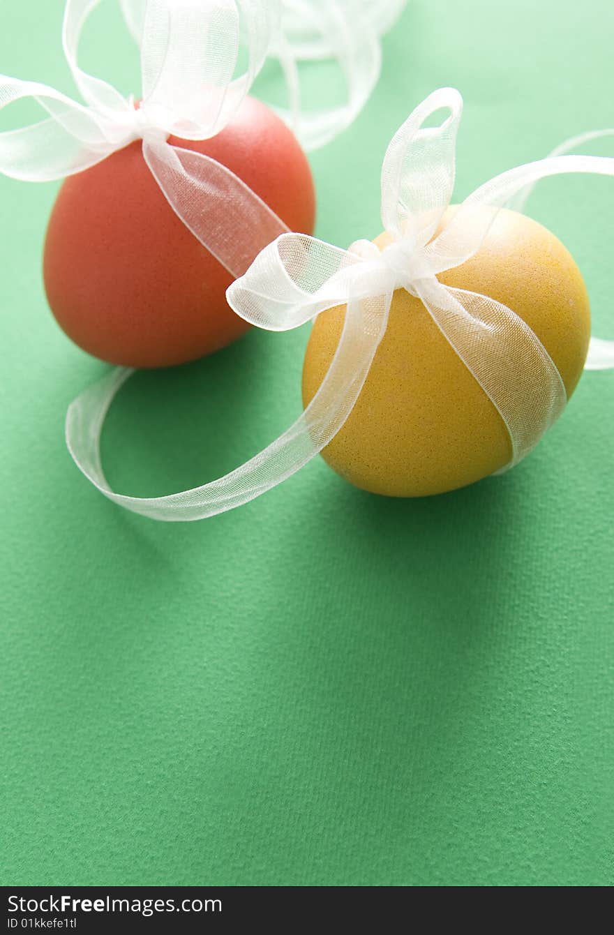 Red & yellow egg with transparent ribbon on green background