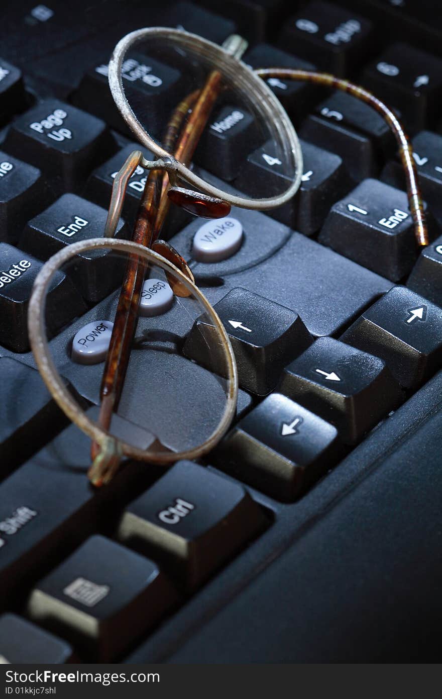 Old spectacles lying on modern black computer's keyboard. Old spectacles lying on modern black computer's keyboard