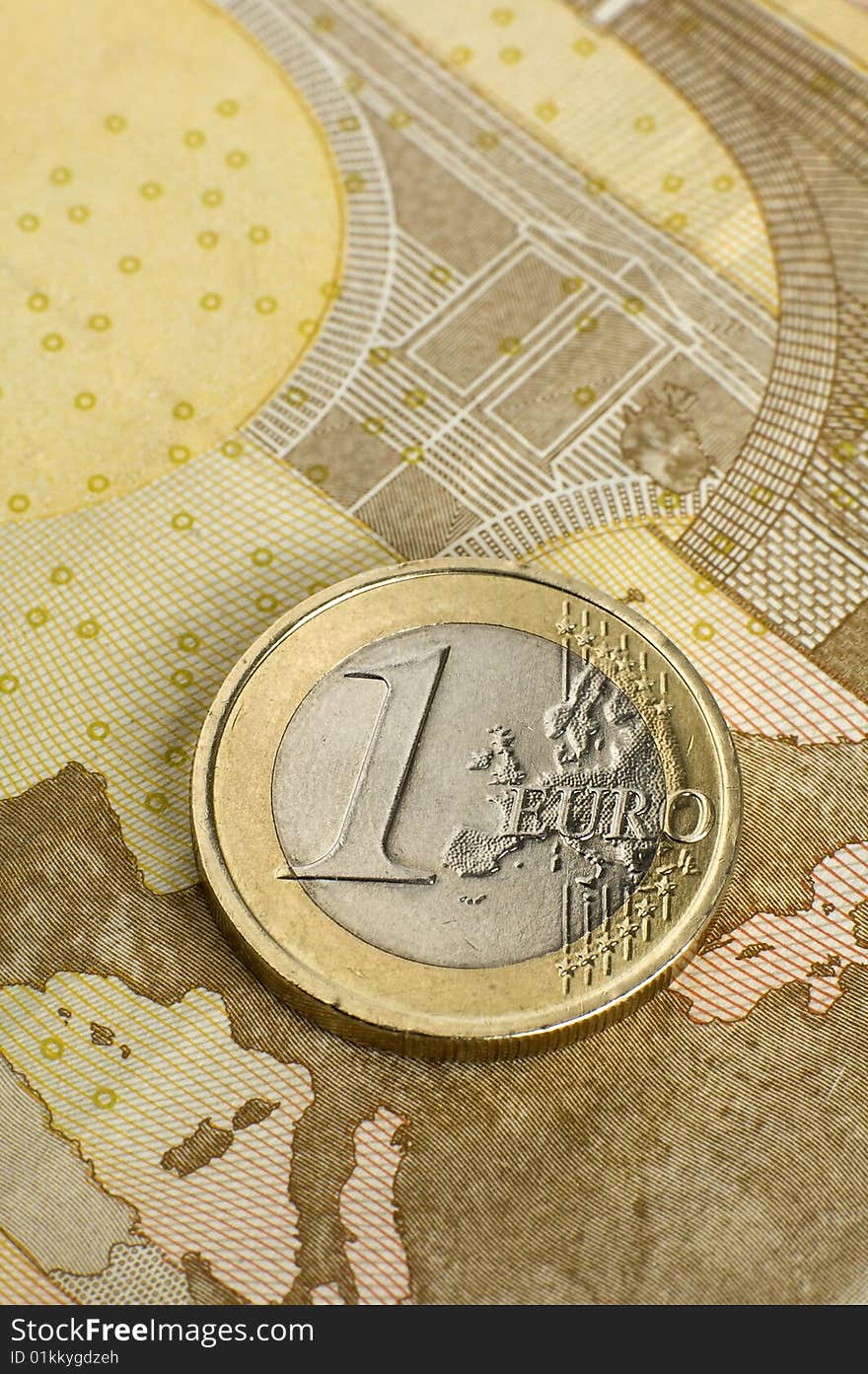 Single one euro coin on fifty euro bank note. Single one euro coin on fifty euro bank note