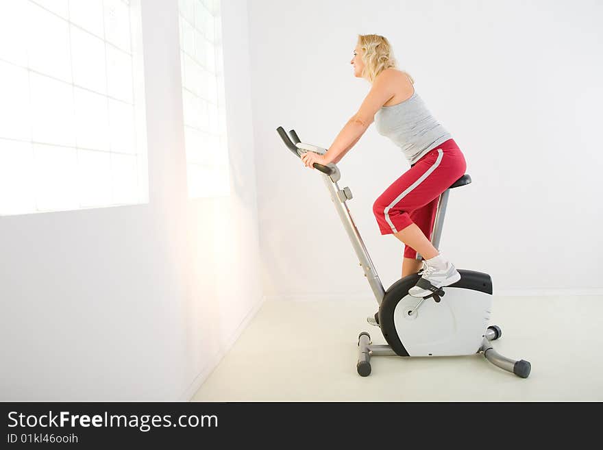 Woman dressed sportswear exercising on spinning bike. She's smiling and looking at camera. Woman dressed sportswear exercising on spinning bike. She's smiling and looking at camera.