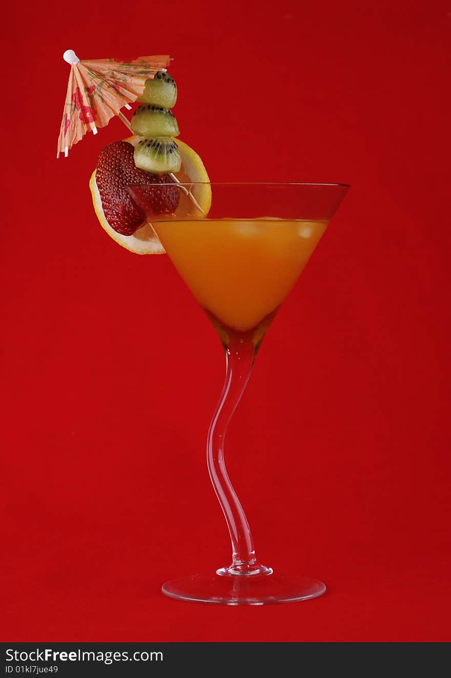 Tropical cocktail with slices of fruit on a red background. Tropical cocktail with slices of fruit on a red background