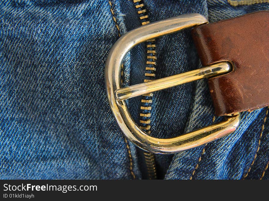 Detail of the metal buckle on blue jeans